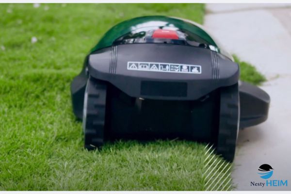 Mähroboter schneidet präzise die Rasenkante entlang eines gepflasterten Gartenwegs